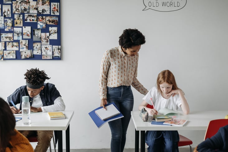 teacher in class helping a girl with her work
